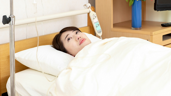病室のベッドで横になっている女性の写真